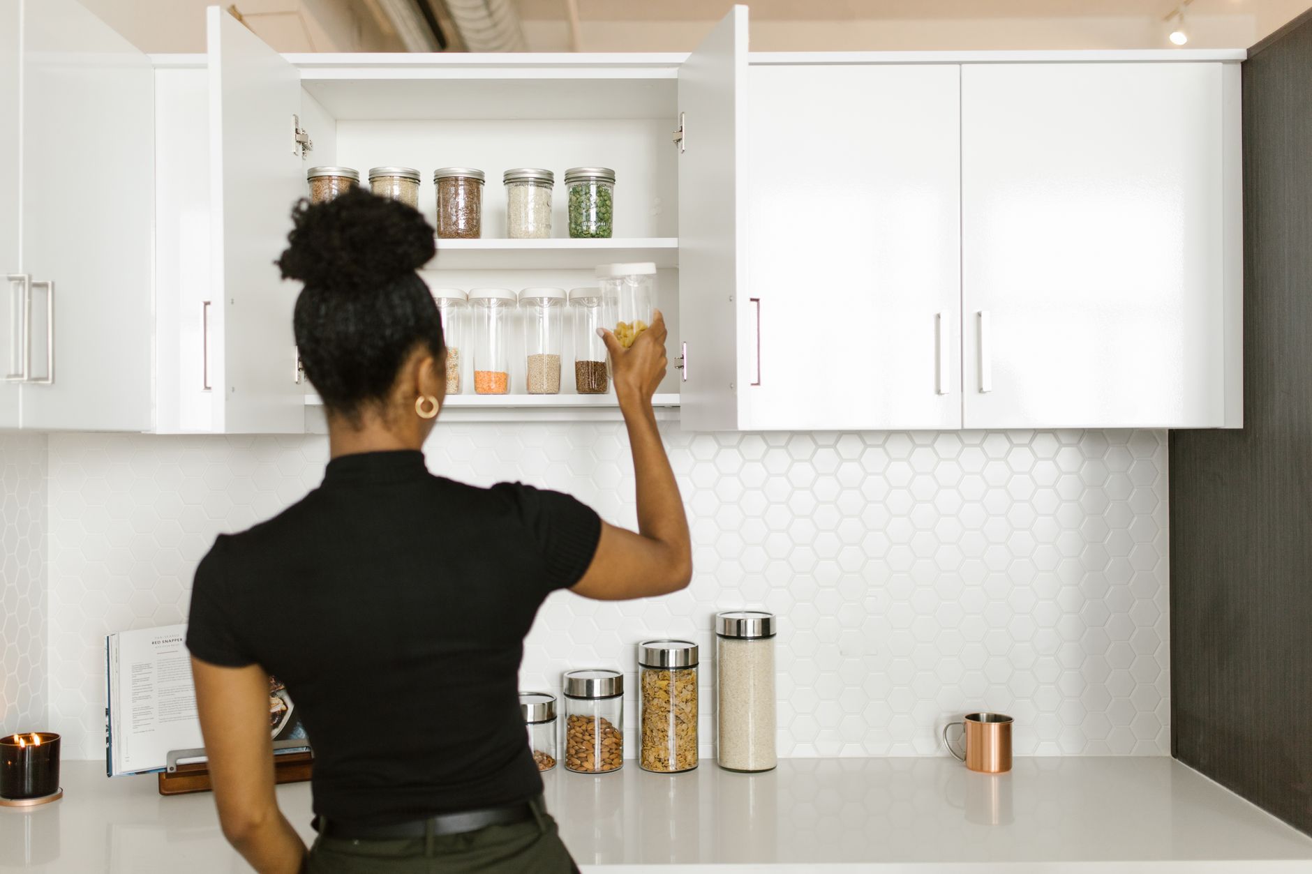 Best can organizer: a woman reaching into a white kitchen cabinet