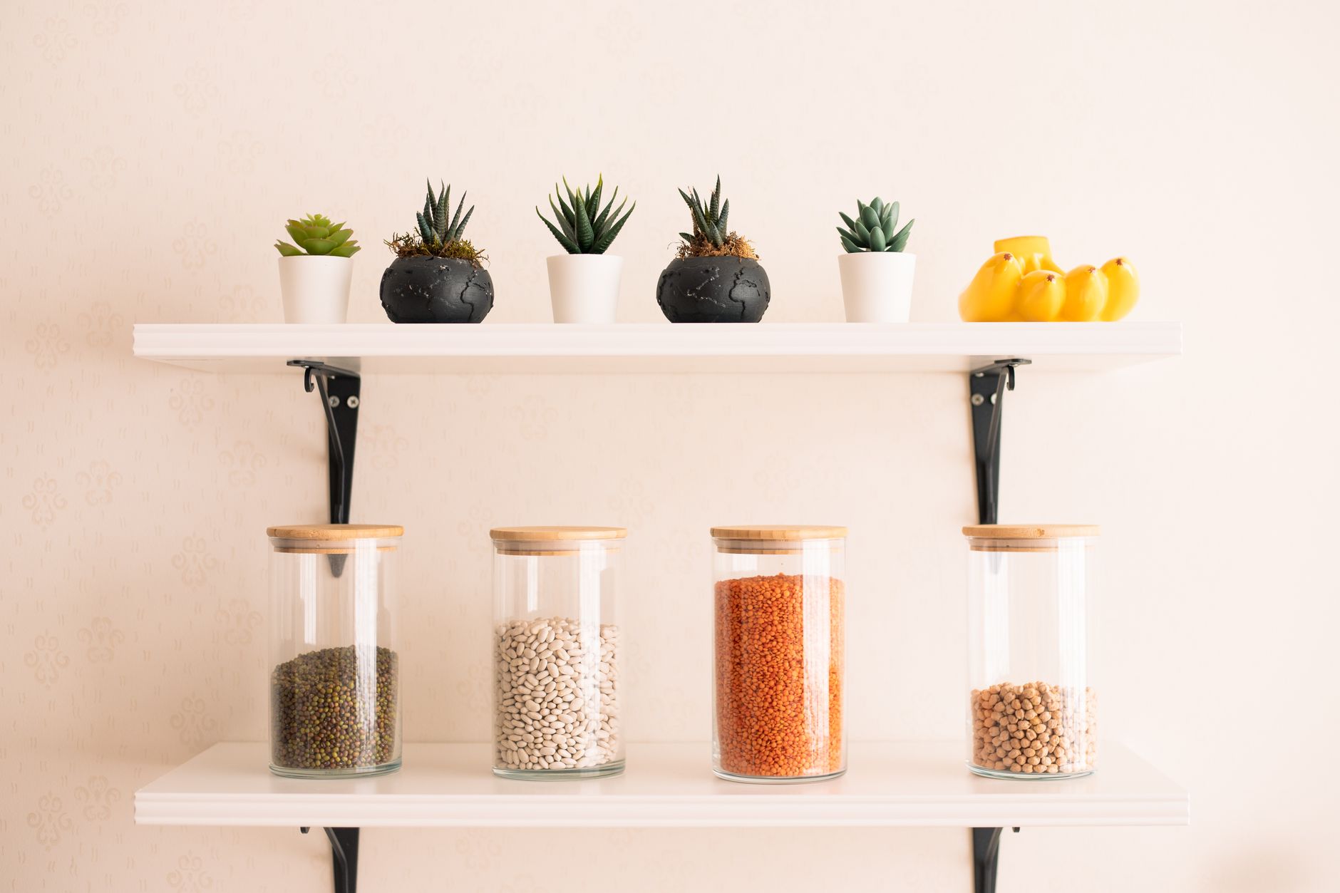 Glass storage jars of dried beans on a wall shelf