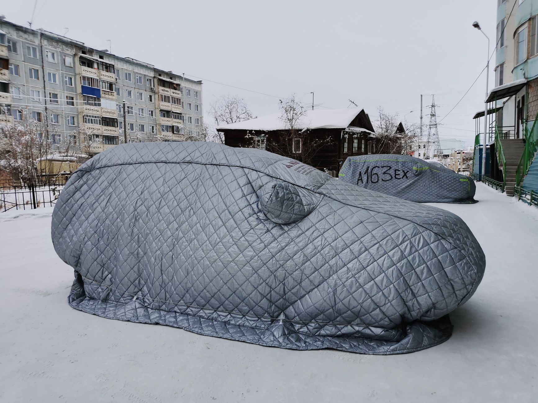 Cars under quilted covers in the snow