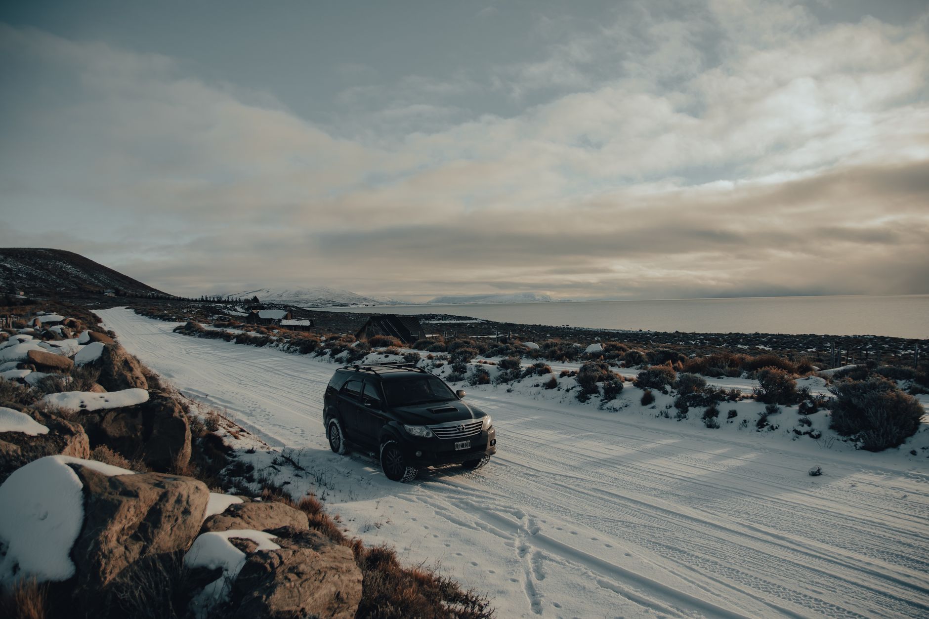 An SUV on a snowy road by the coast