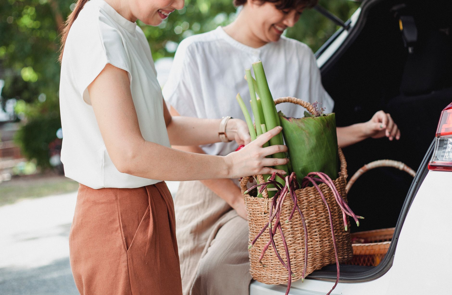 Two women loading a basket into a car trunk