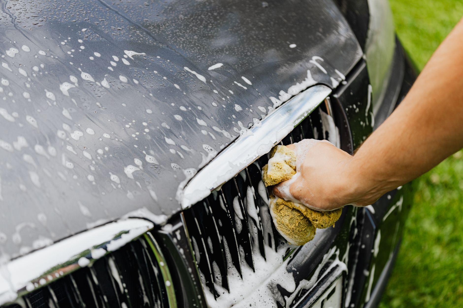 Washing a car with a soapy sponge before waxing