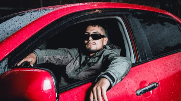 A man leaning out of a red car window in the rain