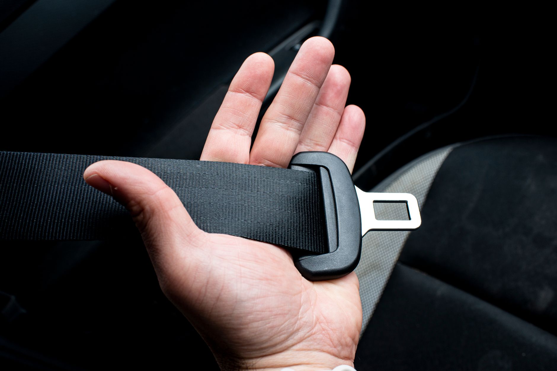 A hand holding a seatbelt buckle