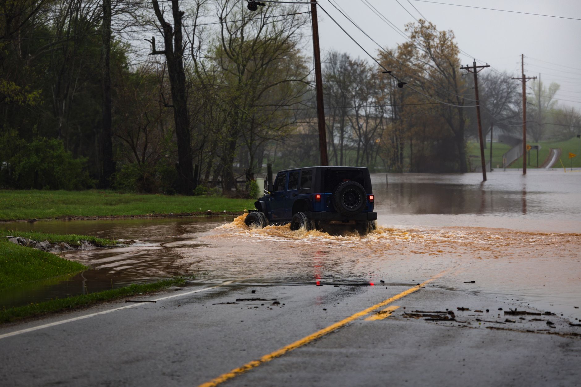 An SUV driving through floodwater on a road