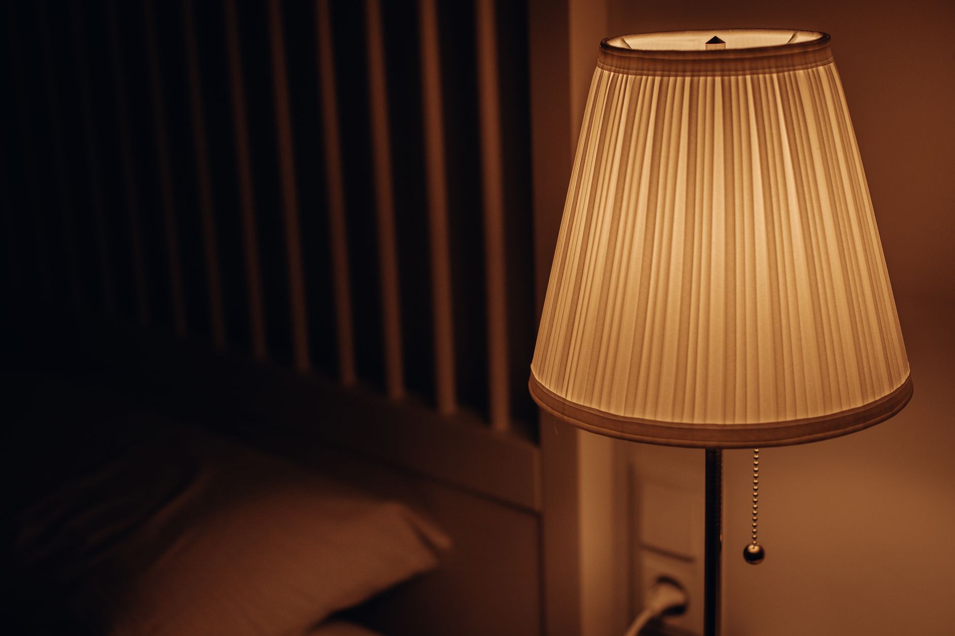 A lamp beside a bed at night