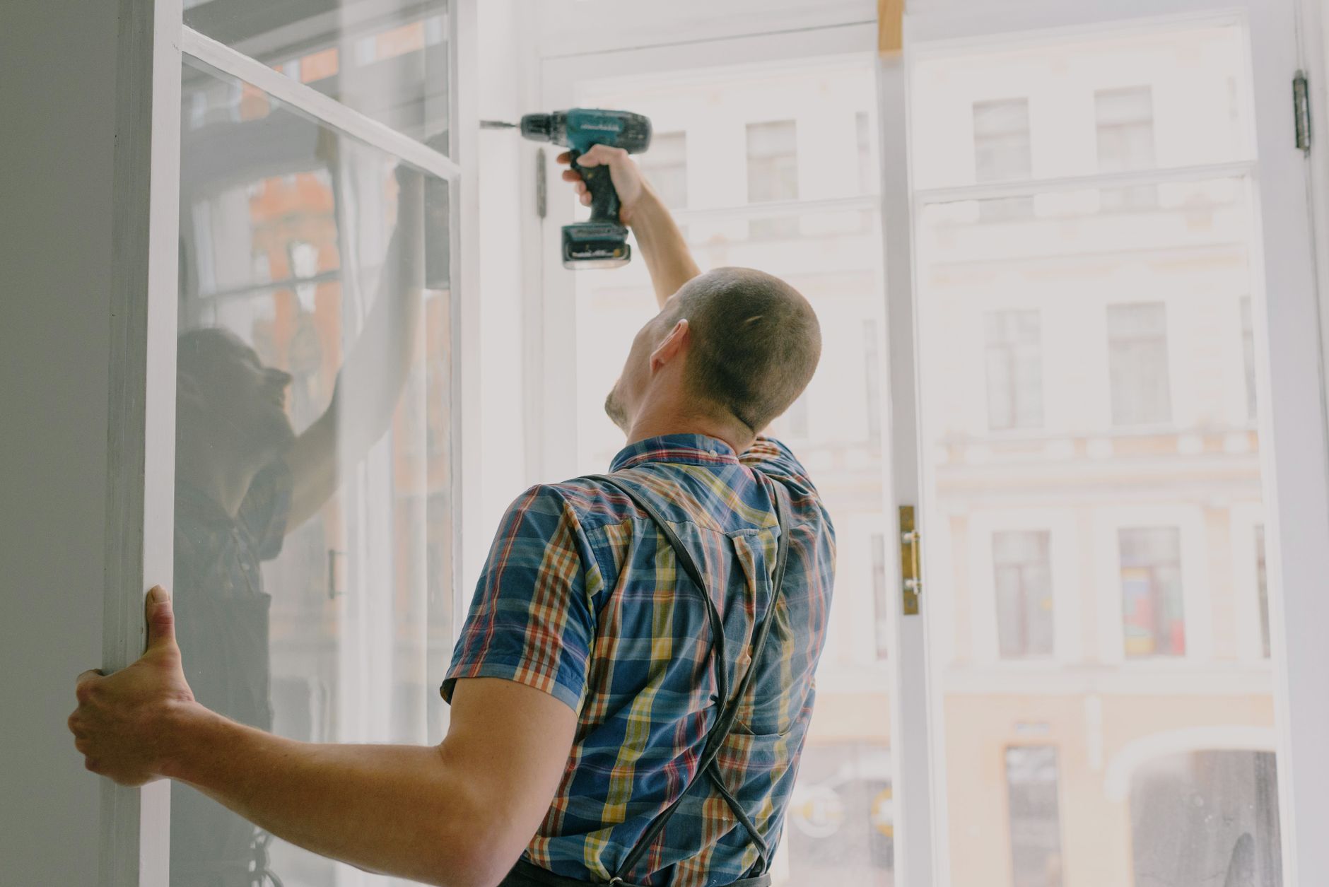 A man using a drill on a window frame