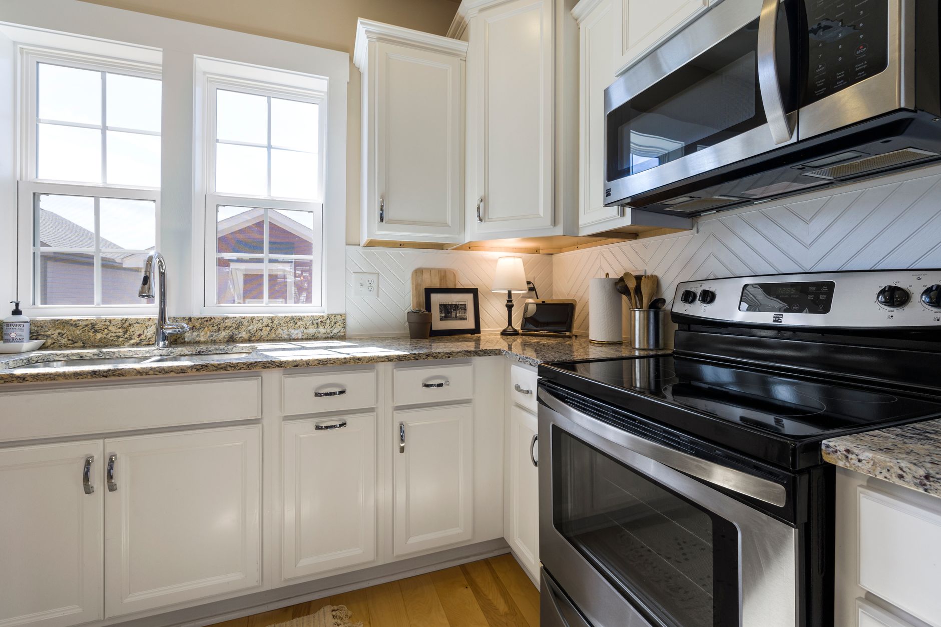A kitchen with white cabinets and stainless appliances