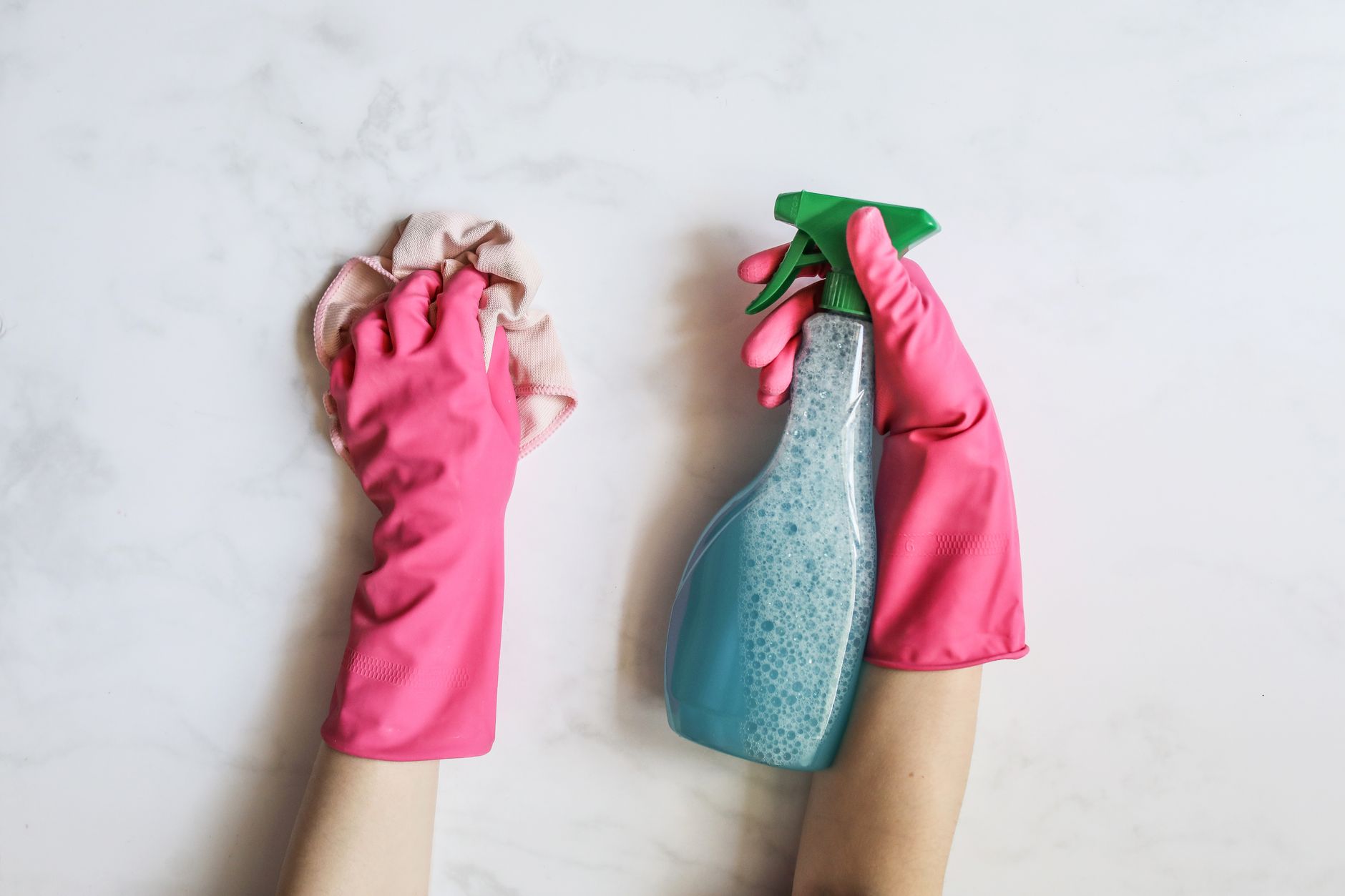 Gloved hands holding a cloth and spray bottle