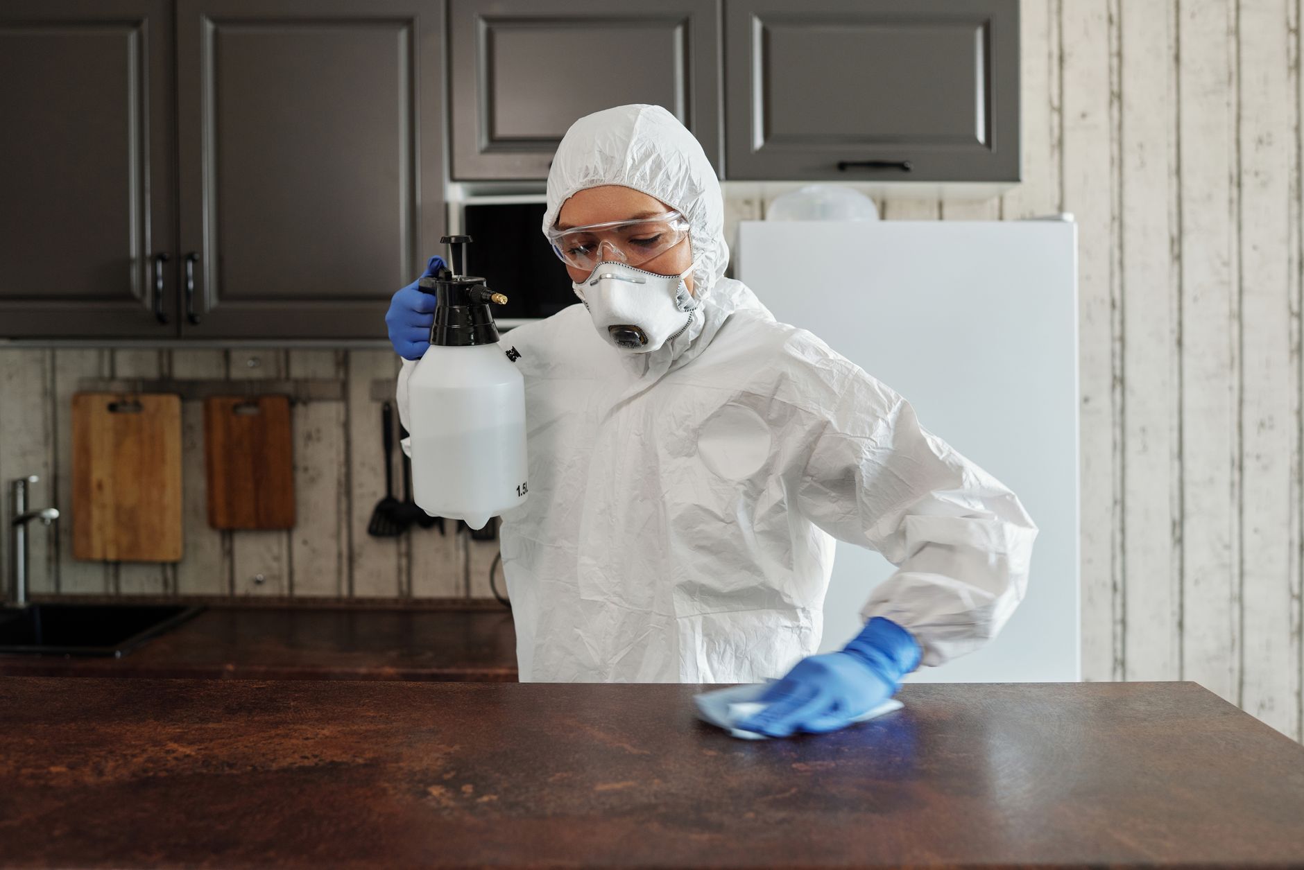 A person in protective gear disinfecting a counter