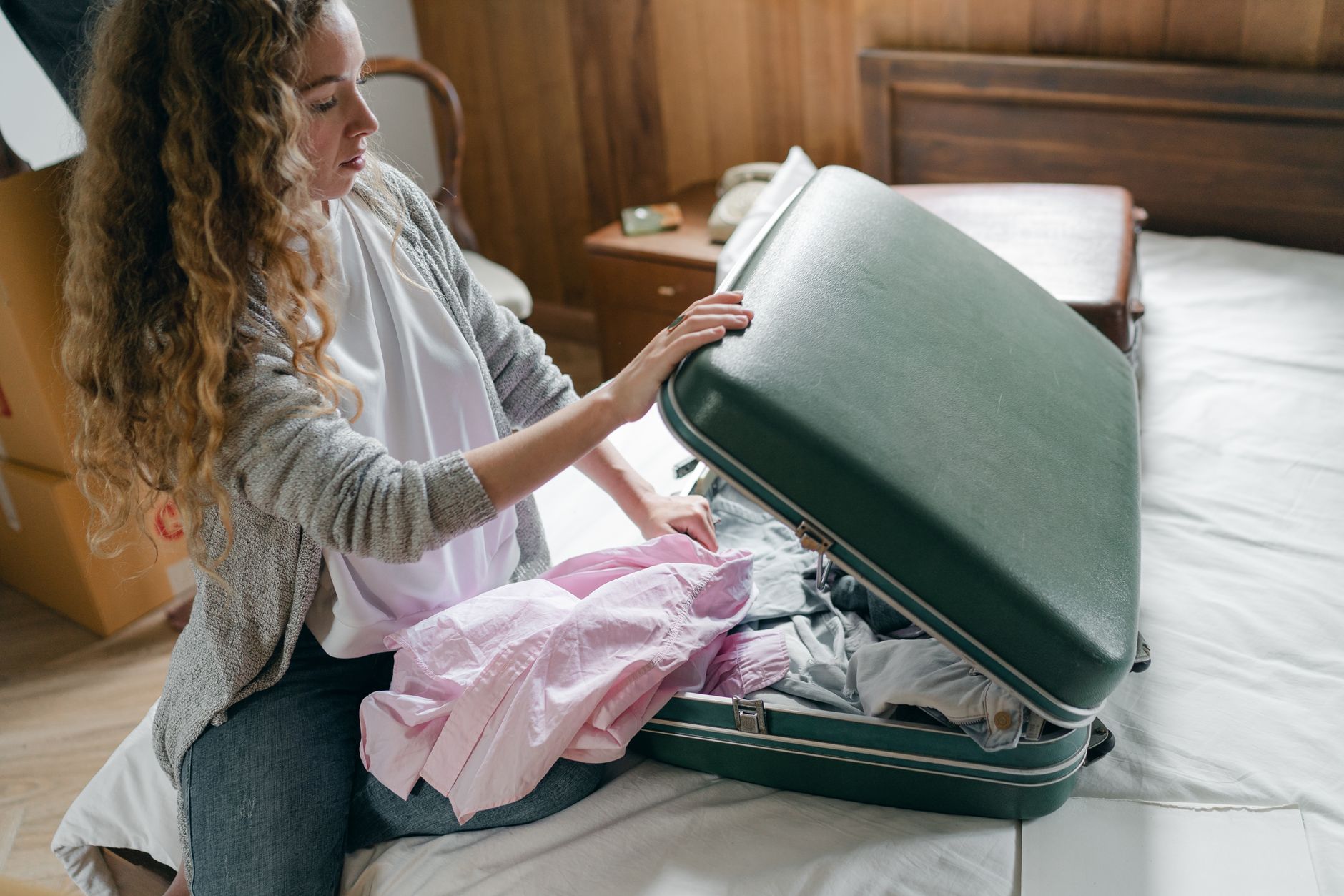A woman packing a suitcase on a bed