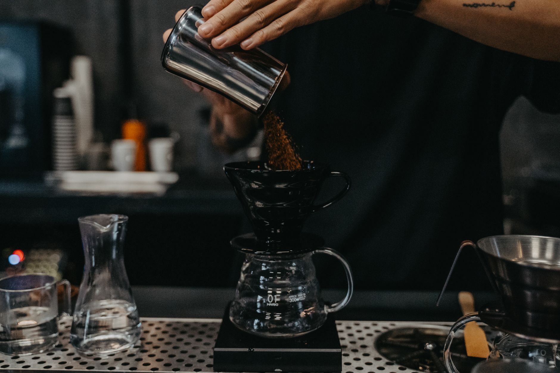 Adding ground coffee to a pour-over brewer above a glass carafe