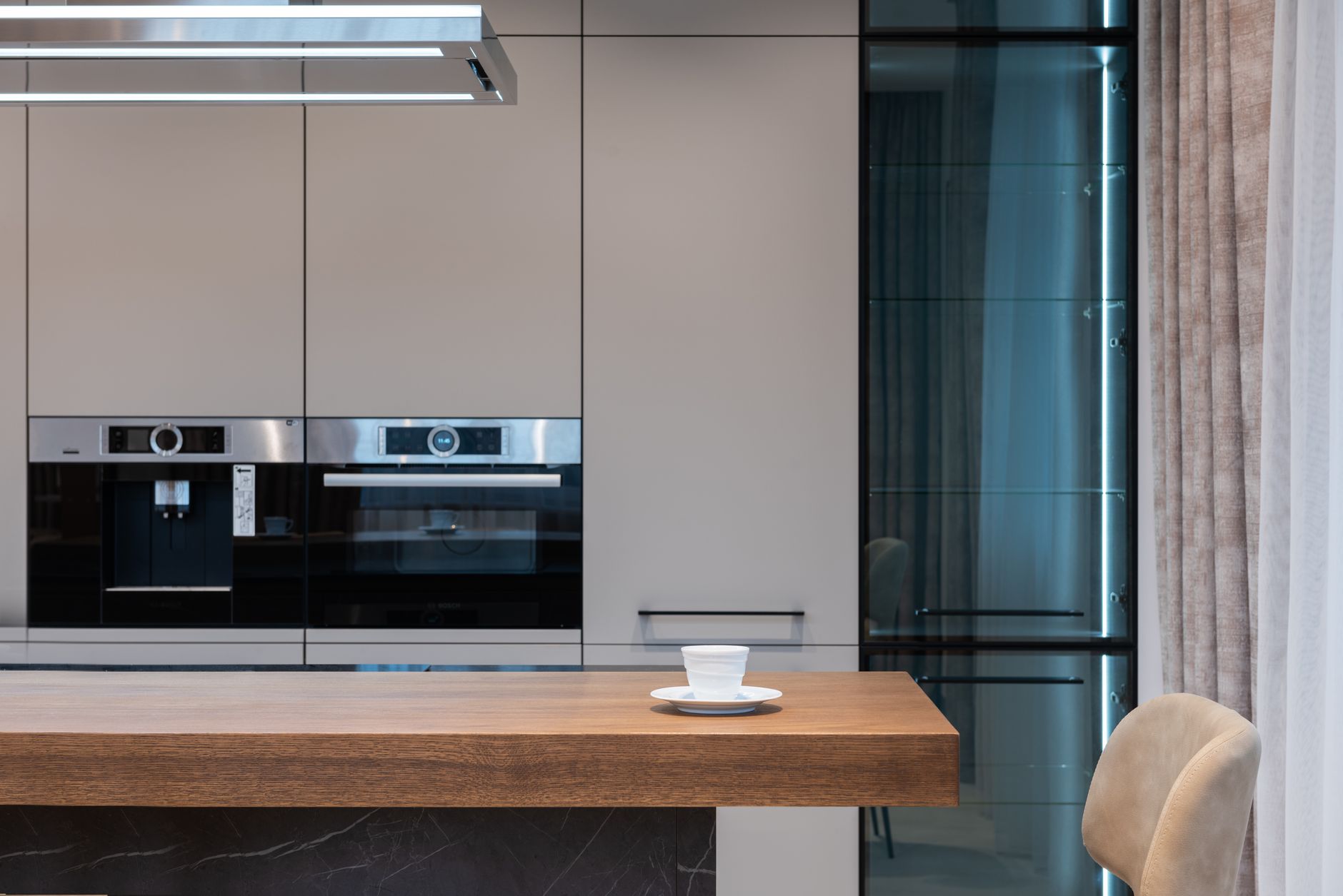 A modern kitchen with built-in ovens and a coffee cup