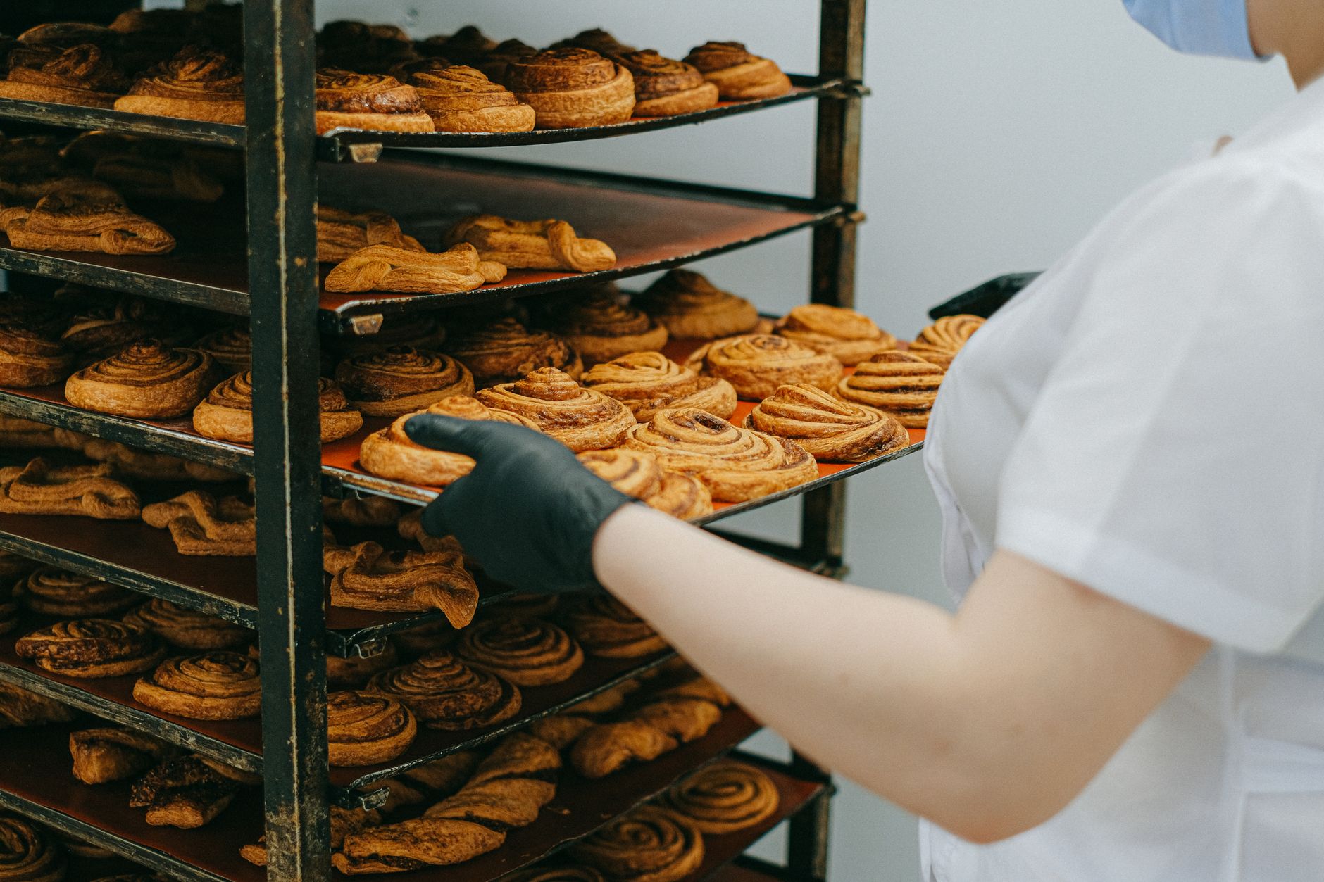 A baker pulling a tray from a rack