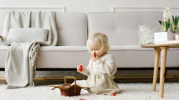 A toddler playing on a rug by a sofa