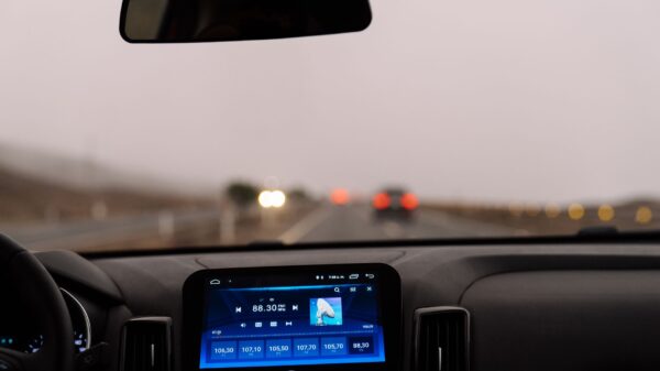 A dashboard screen and rear view mirror on a misty highway