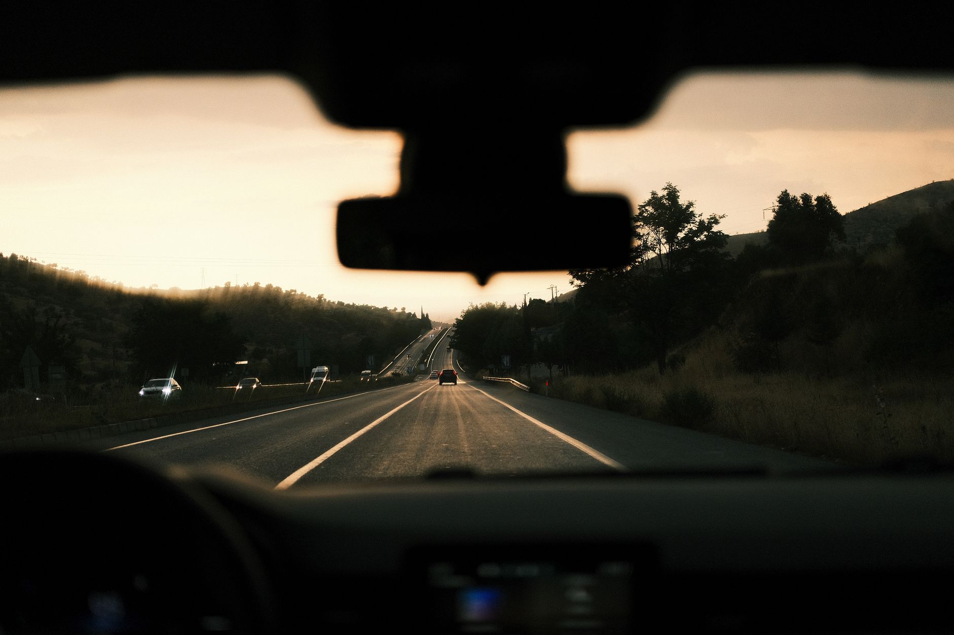 The road ahead seen through a windshield at dusk