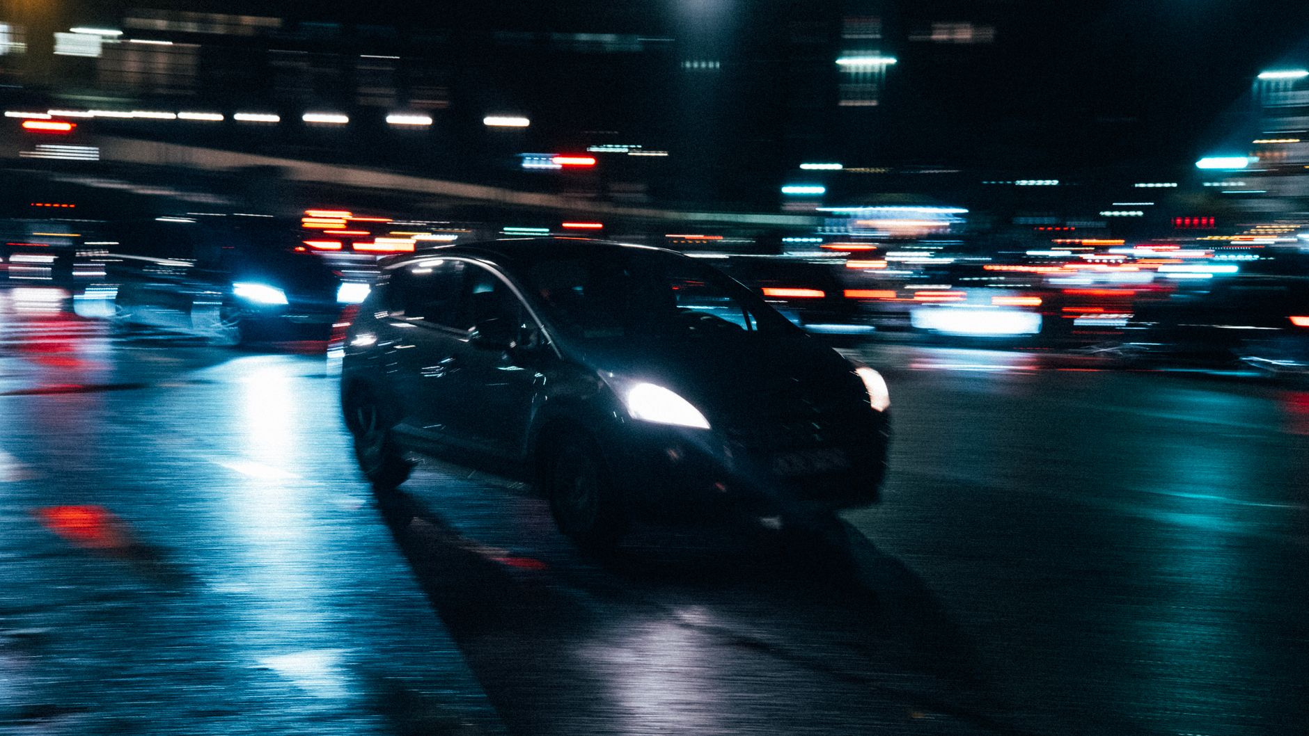 A car driving through wet city streets at night