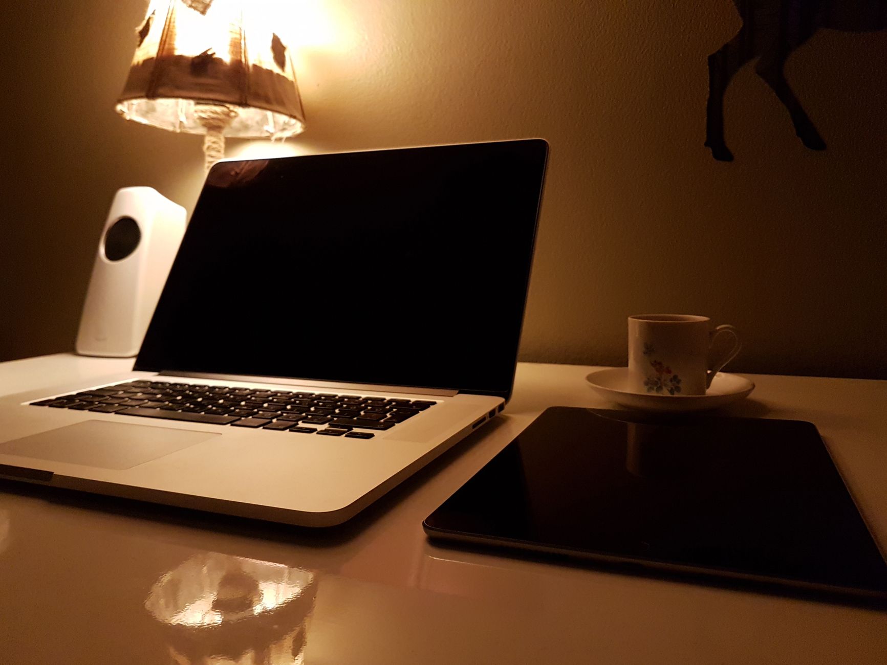 A laptop and tablet under a lamp