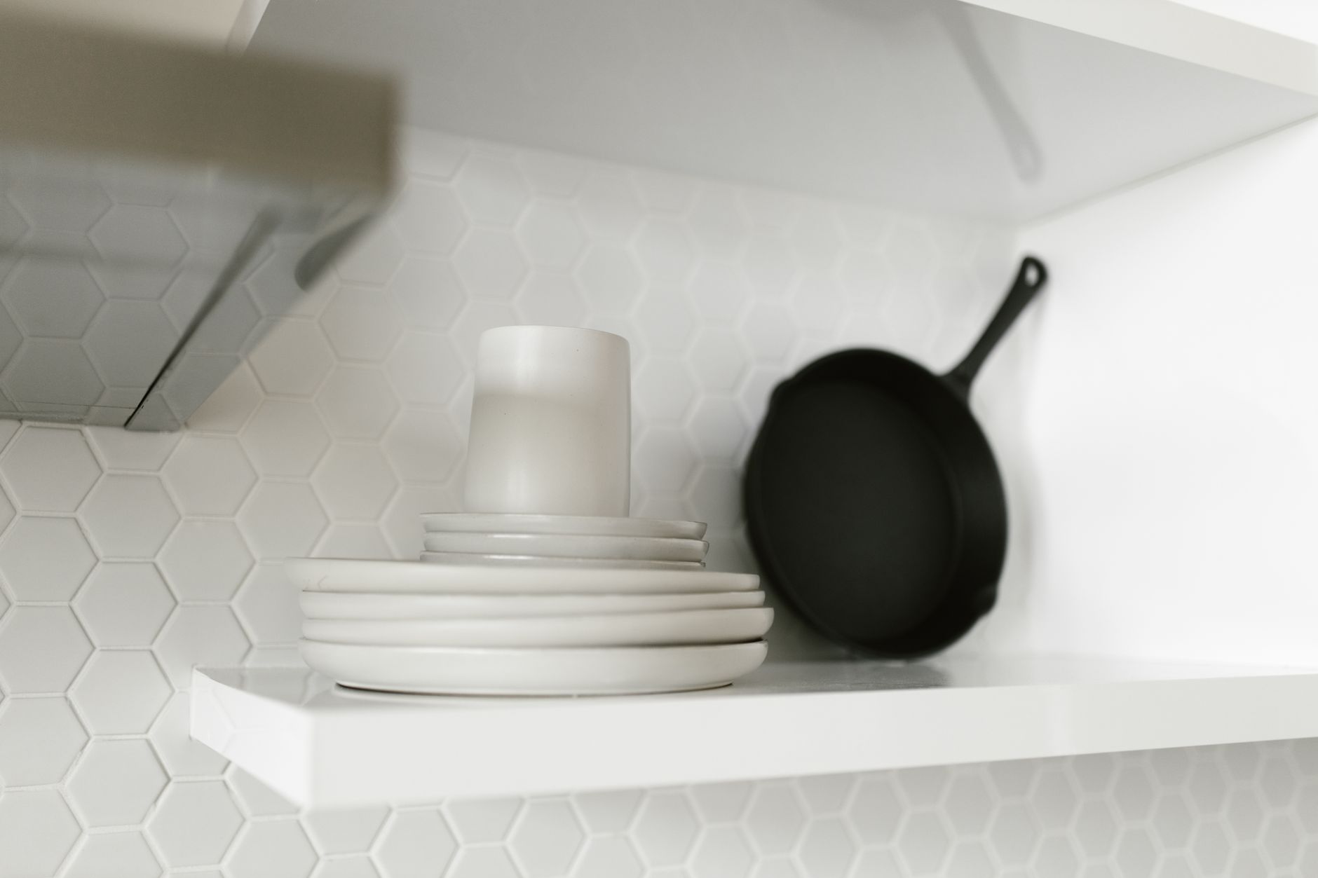 Plates and a skillet on a white shelf
