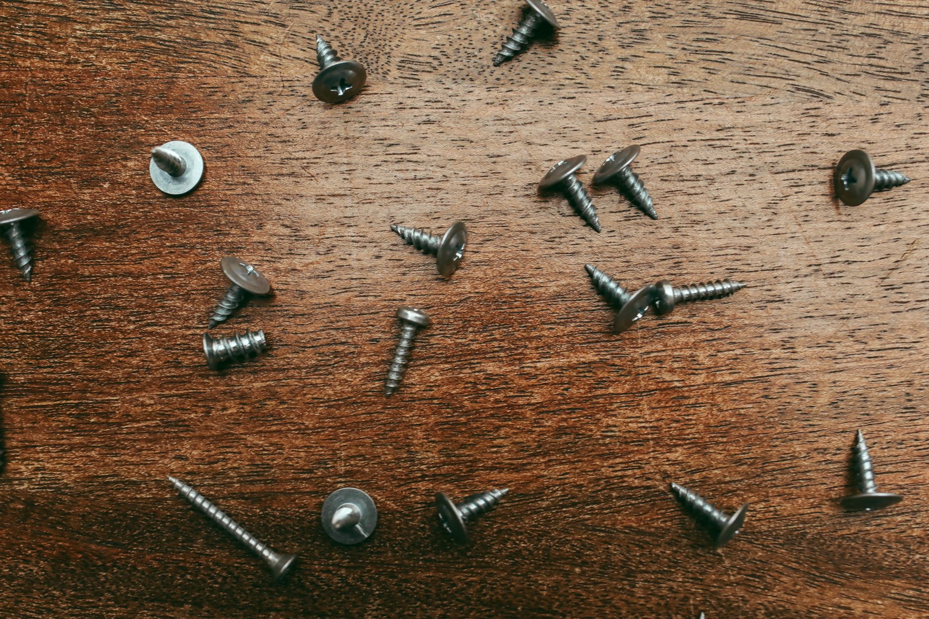 Loose screws scattered on a wooden surface