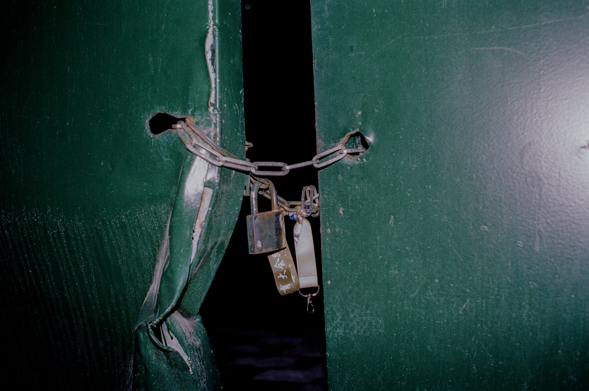 A chain and padlocks holding two green doors shut