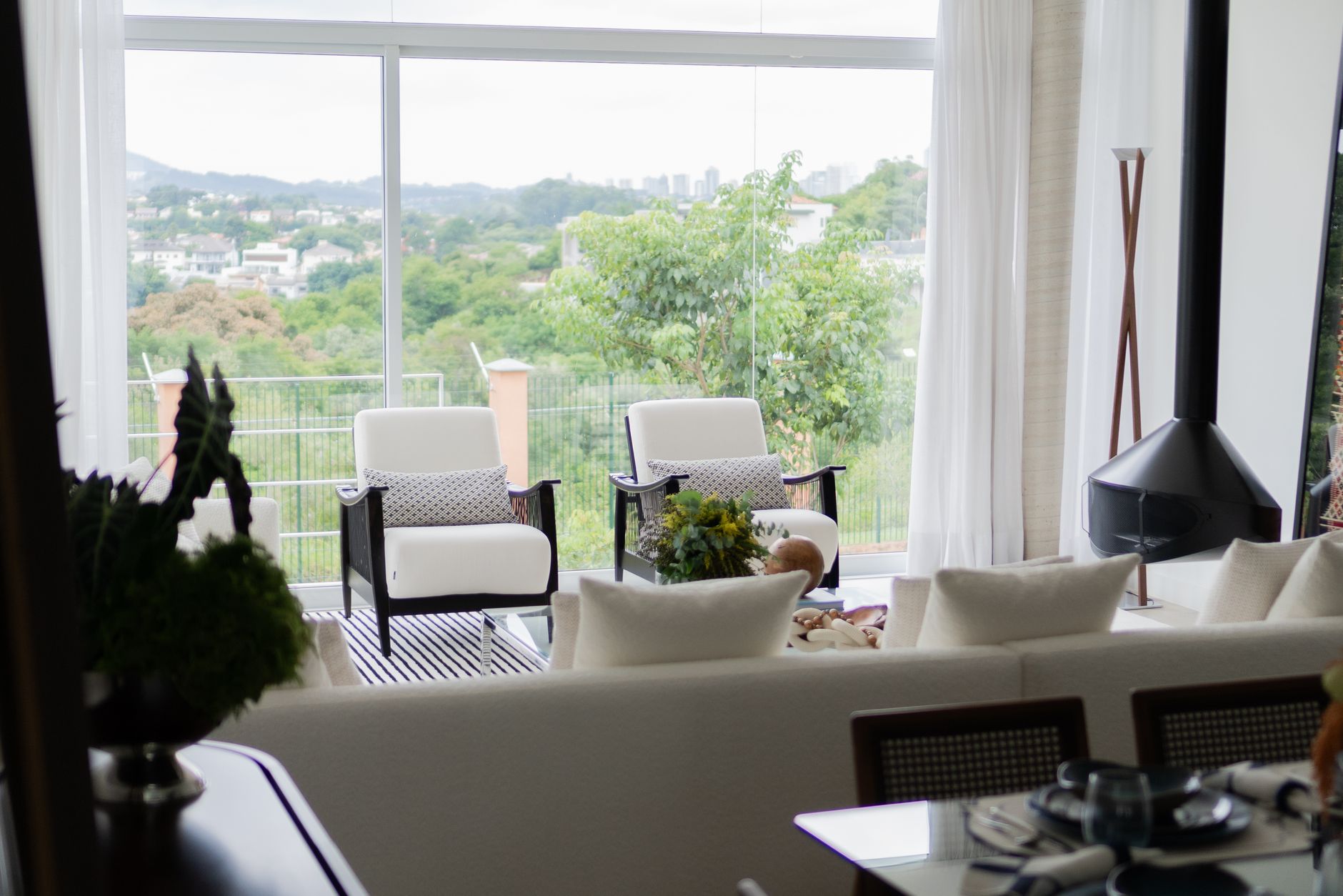 A living room with tall windows overlooking trees