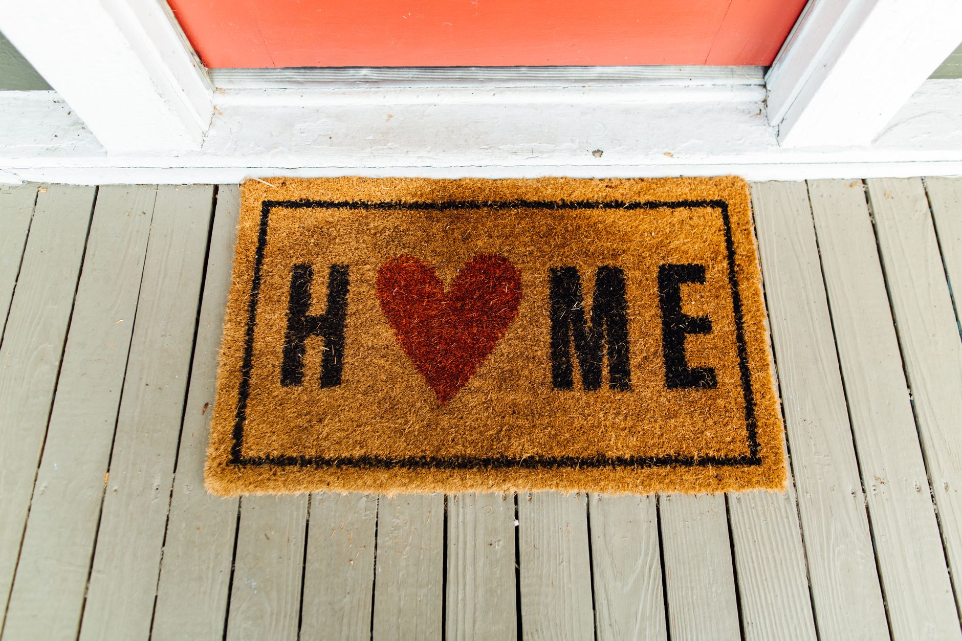 A coir doormat with a heart design on a porch