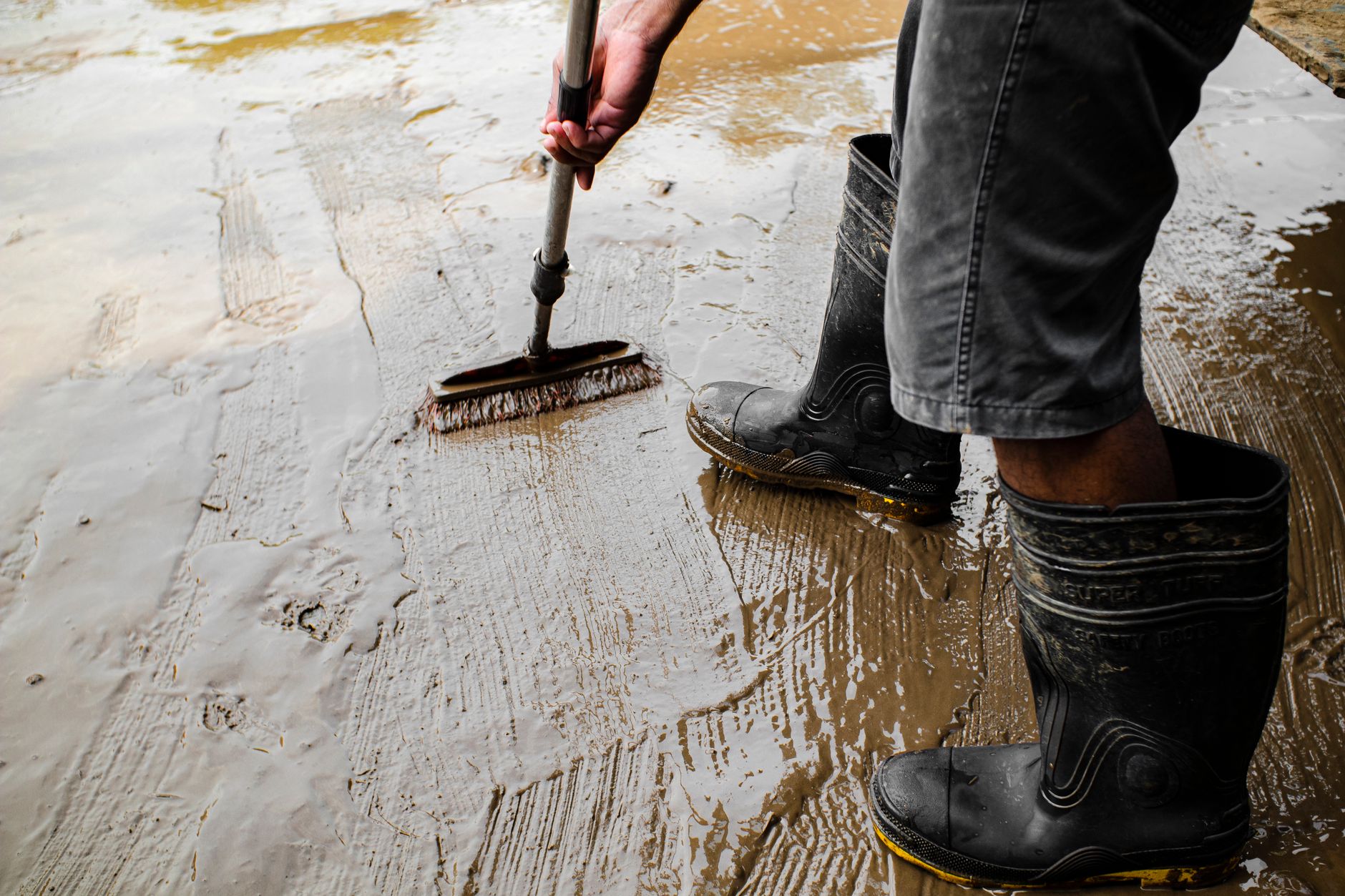 Scrubbing a muddy floor in rubber boots