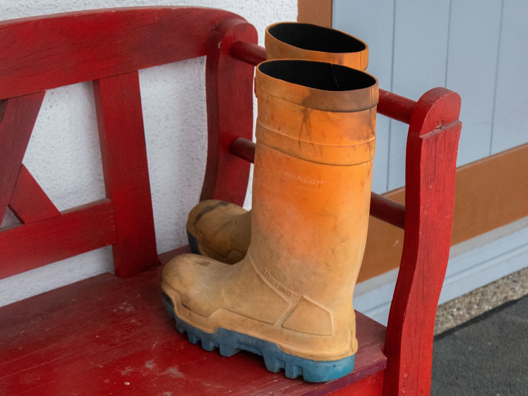 Rubber boots on a red bench by a door