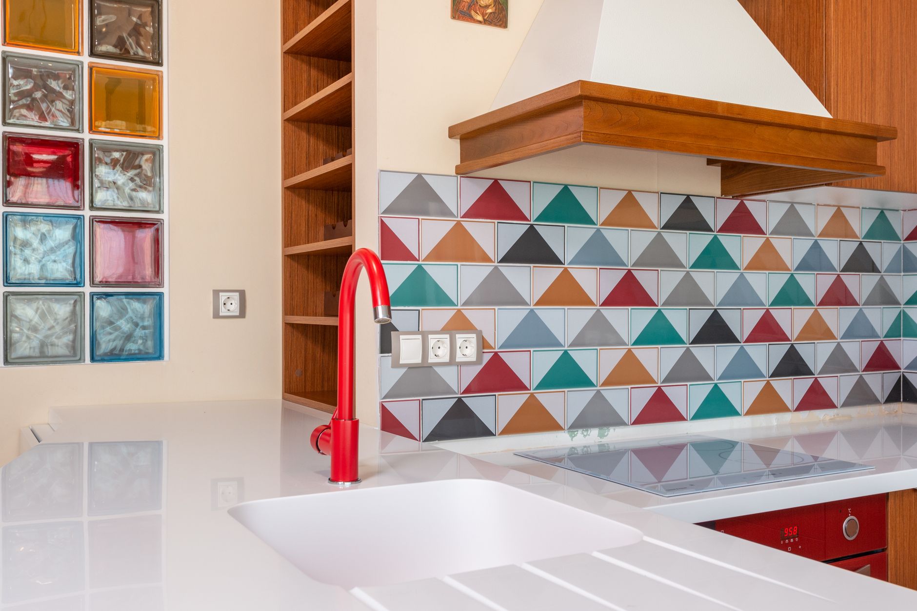 A bright kitchen with a red faucet and patterned backsplash