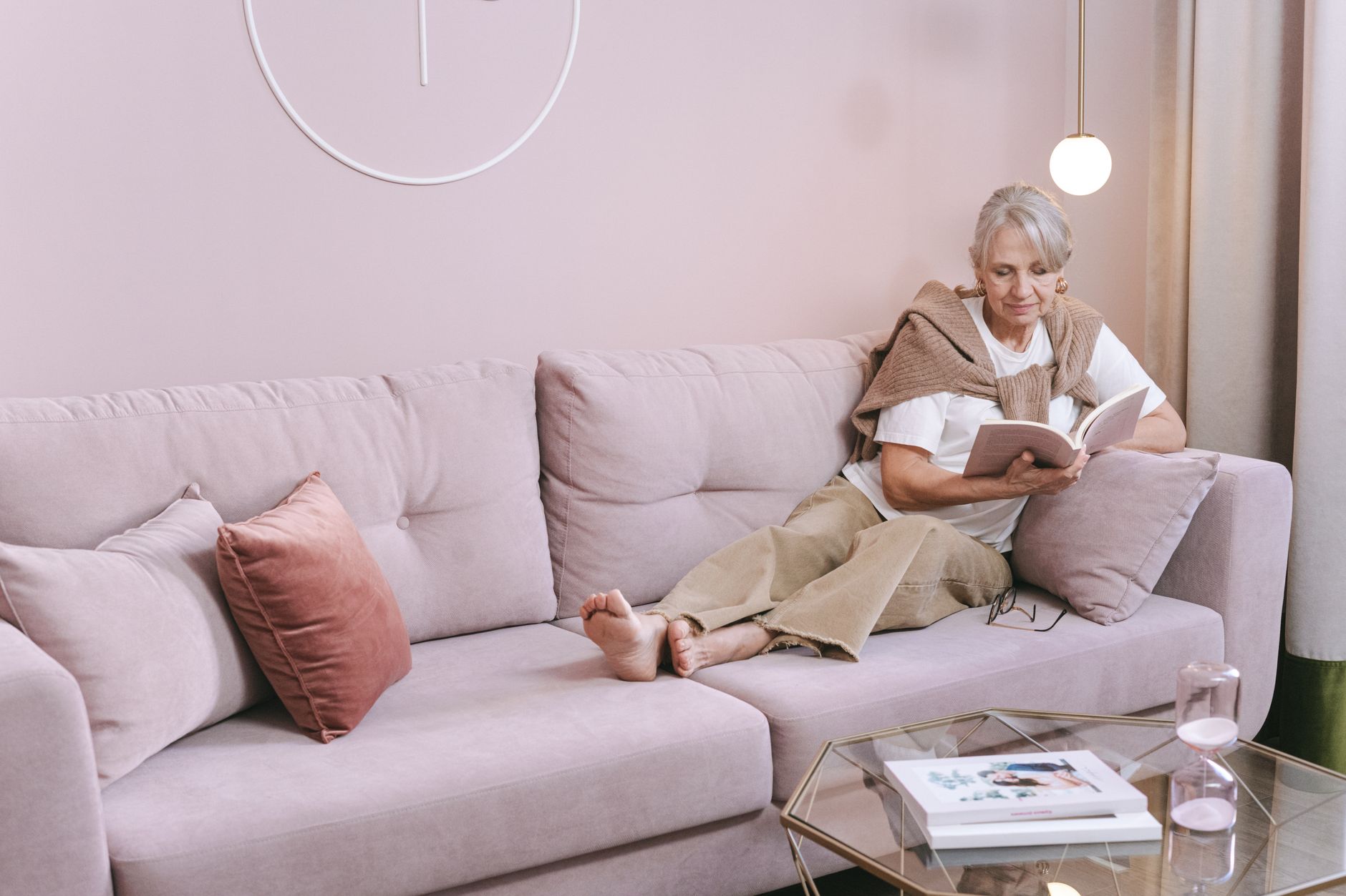 A woman reading on a pink sofa