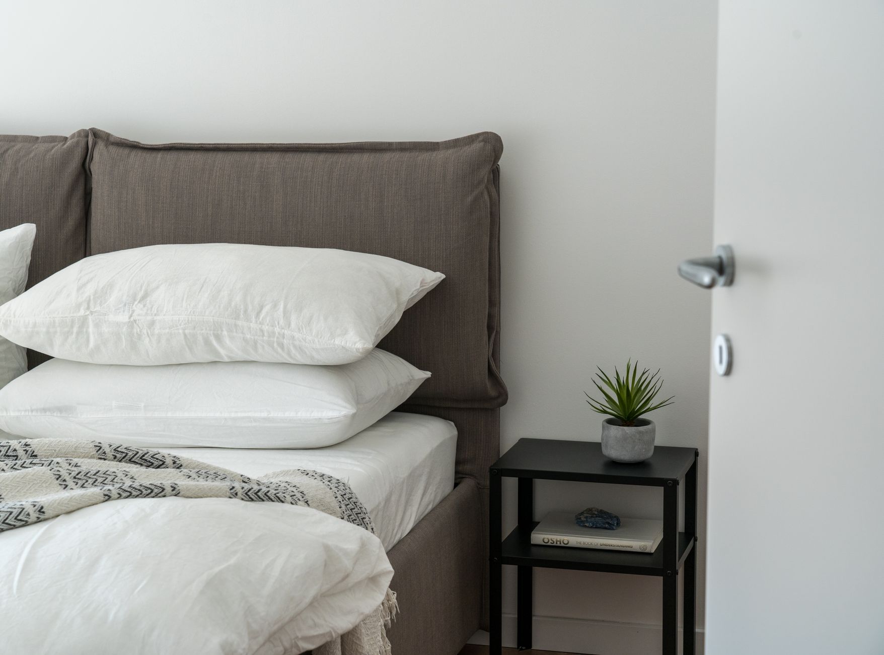 A bed with white bedding and pillows in a bright room