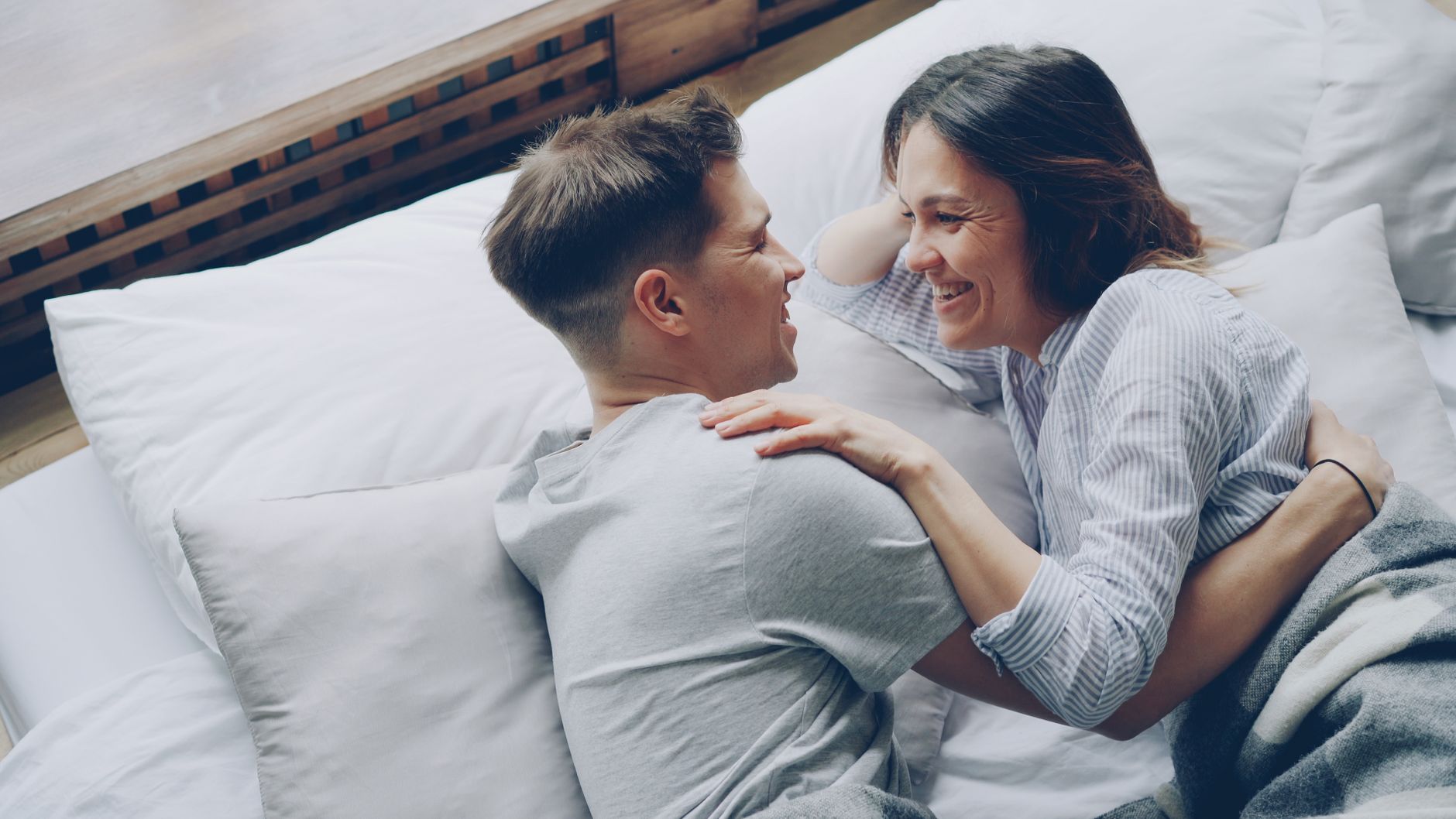 A couple laughing together in bed