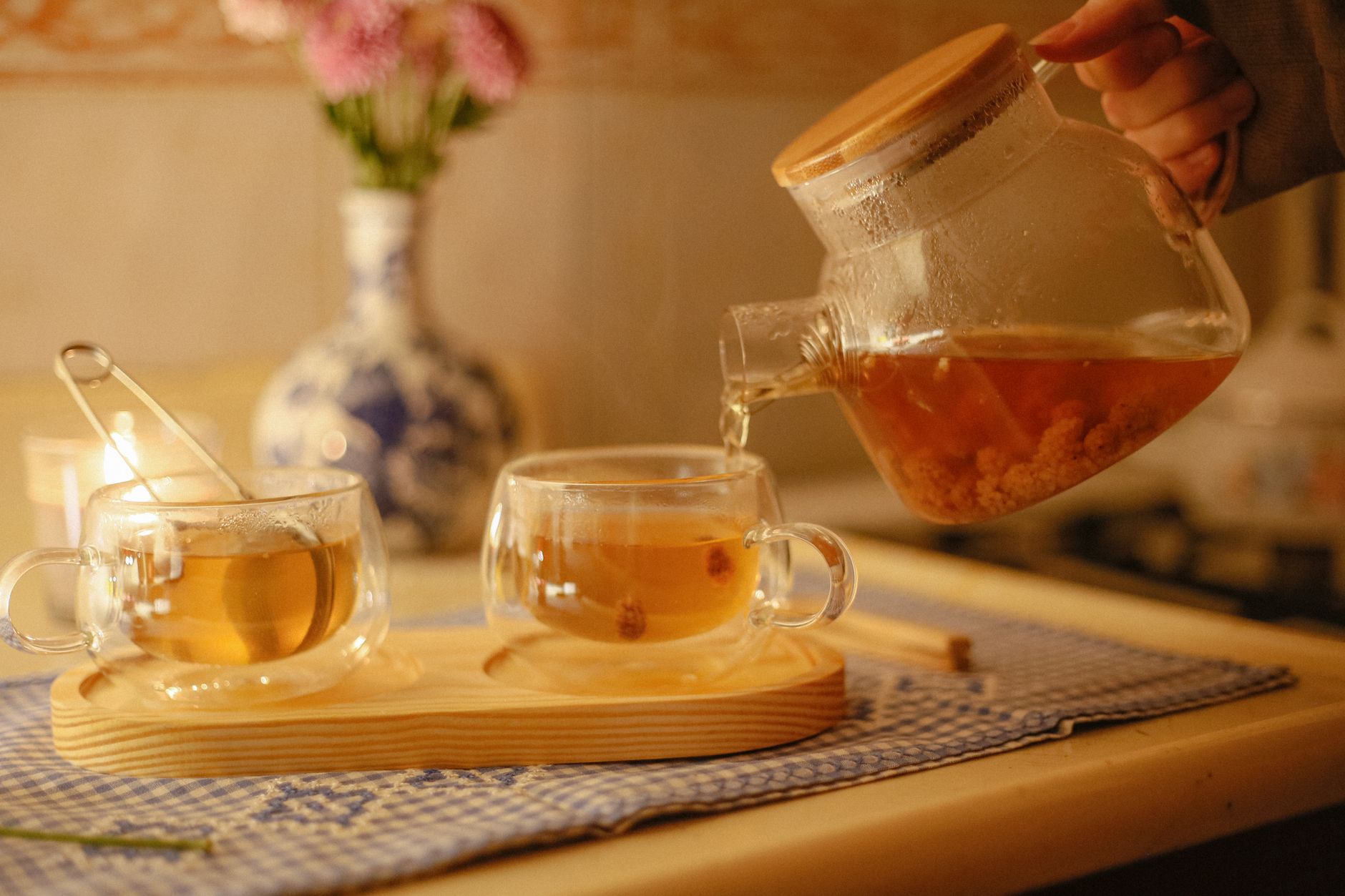 Pouring tea from a glass teapot into cups