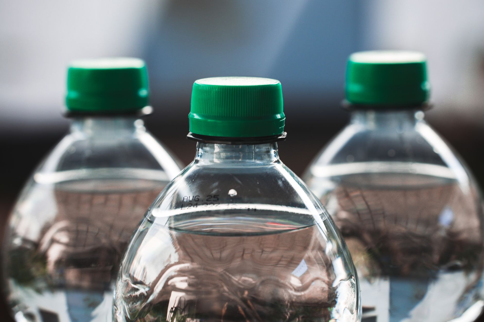 Three plastic water bottles with green caps