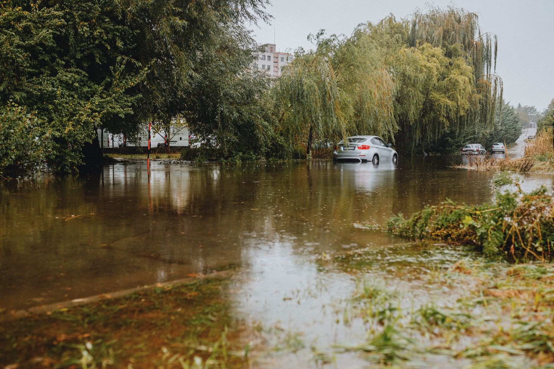 A flooded street with a car stuck in the water