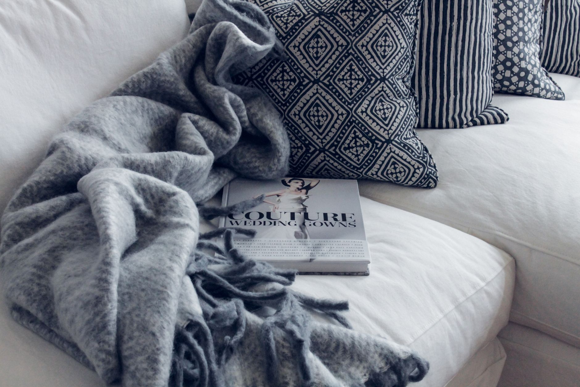 A throw blanket and pillows on a white sofa