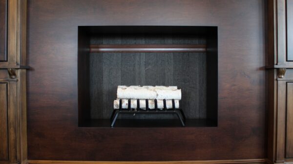 Best fake fireplace logs: birch logs on a grate in a wood-paneled firebox