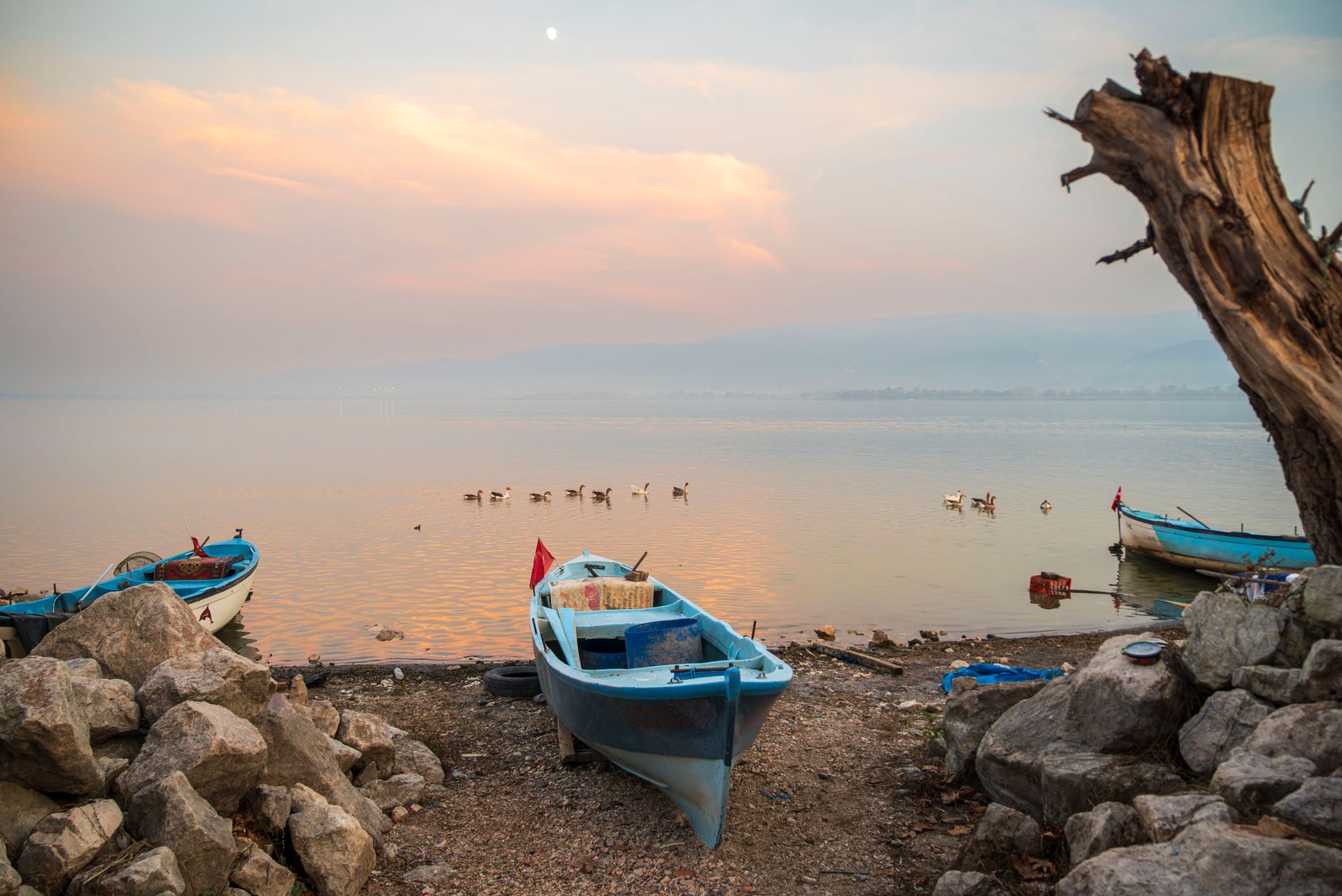 Small boats on a lake shore at sunset