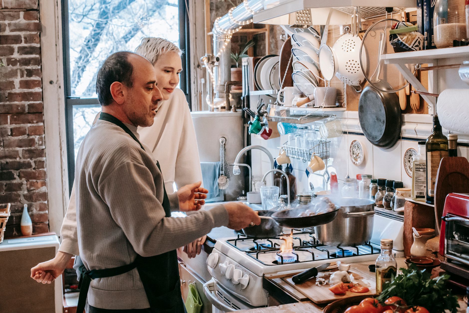 A couple cooking at a gas stove