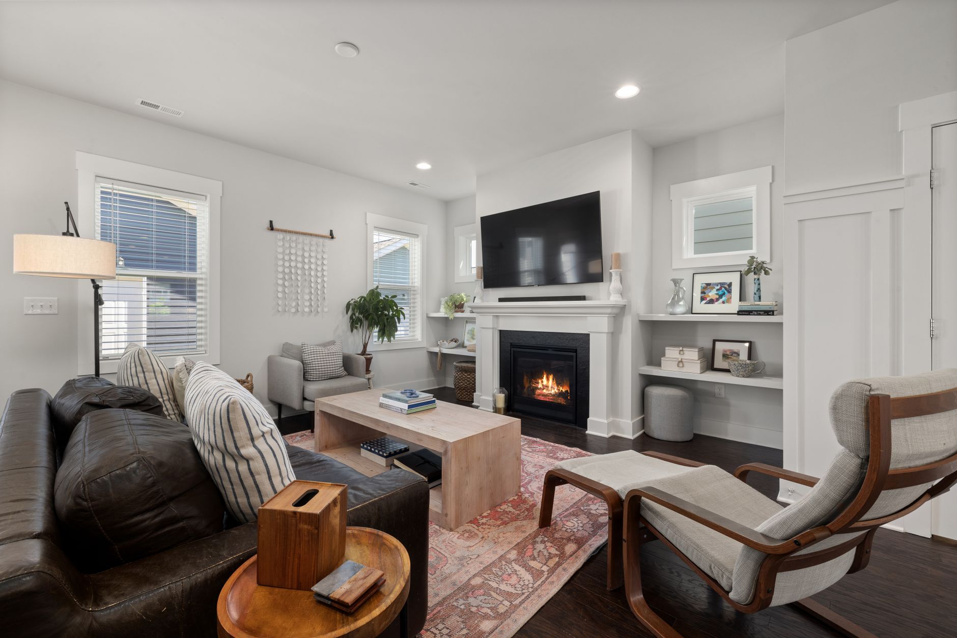 A living room with a gas fireplace below a TV