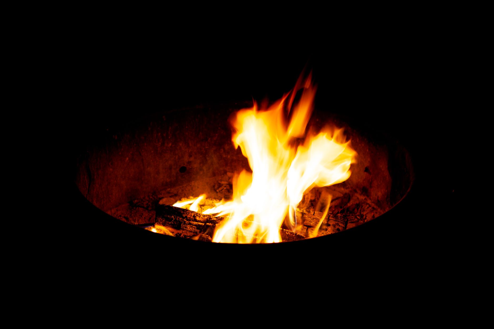 Flames and glowing embers in an outdoor fire pit
