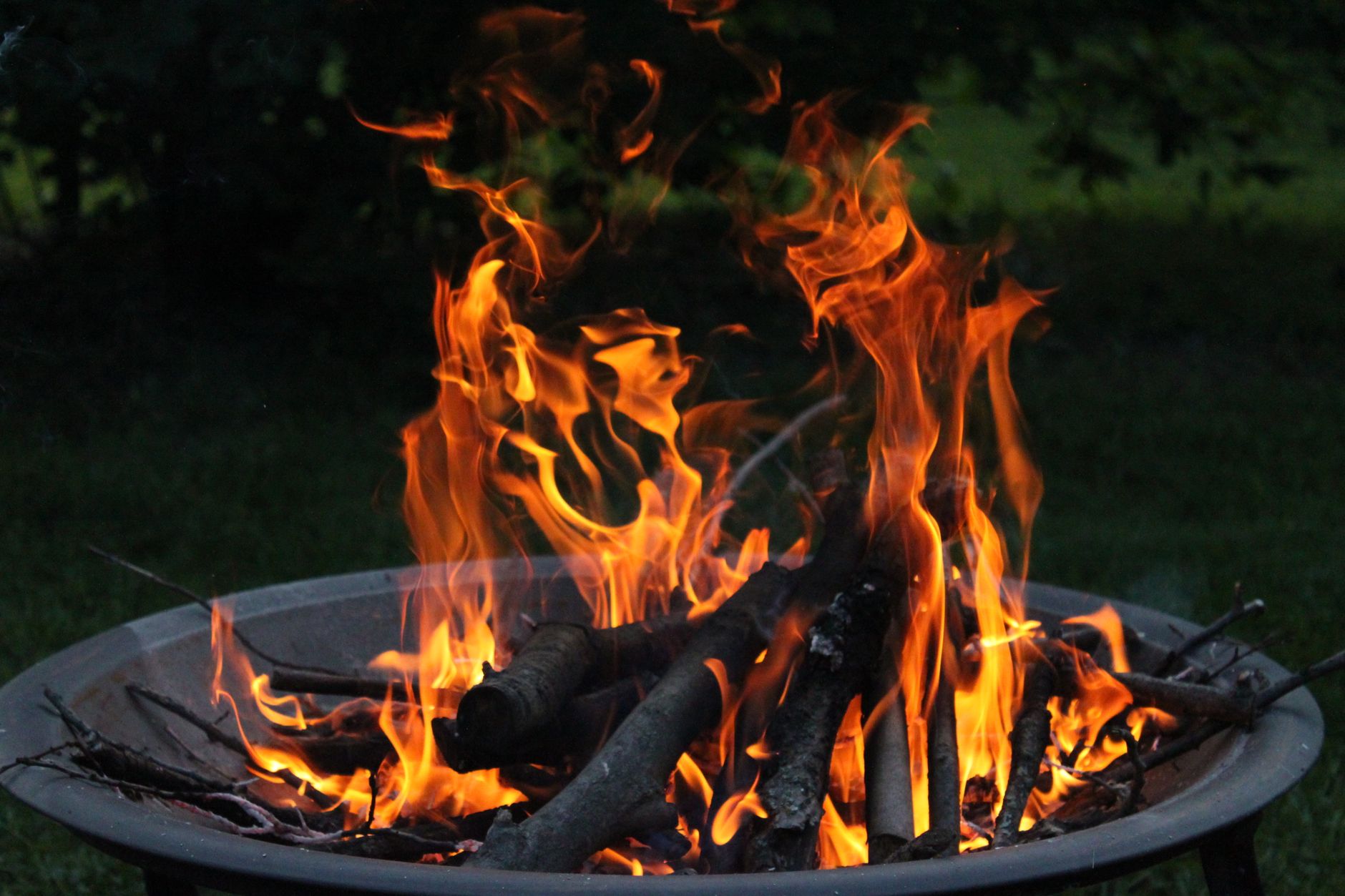 Best fire pit: a wood fire burning in a backyard fire pit at dusk