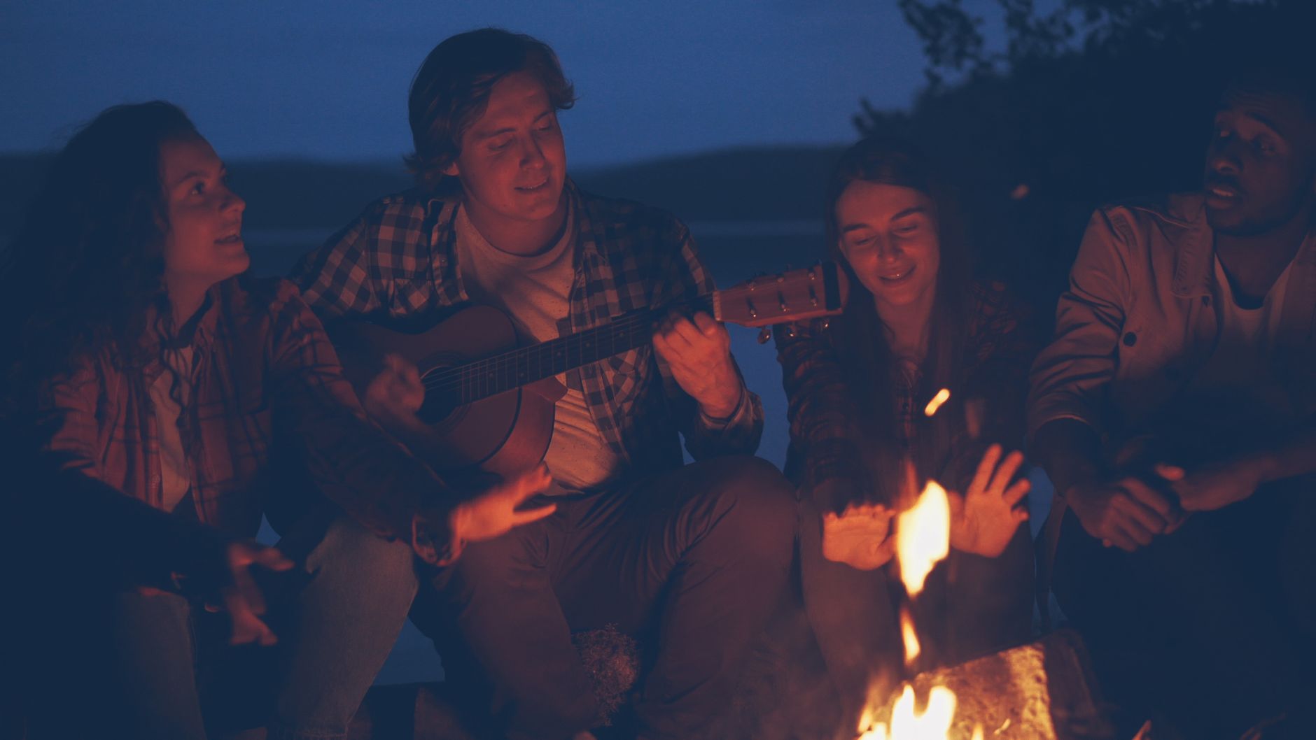People sitting around an outdoor fire at night