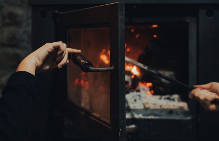 Best fireplace glass cleaner: opening a wood stove door to tend the fire