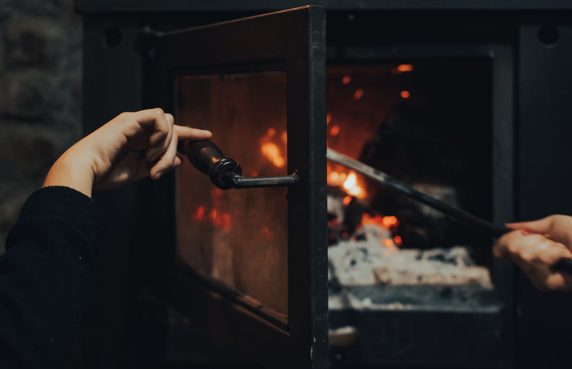 Best fireplace glass cleaner: opening a wood stove door to tend the fire
