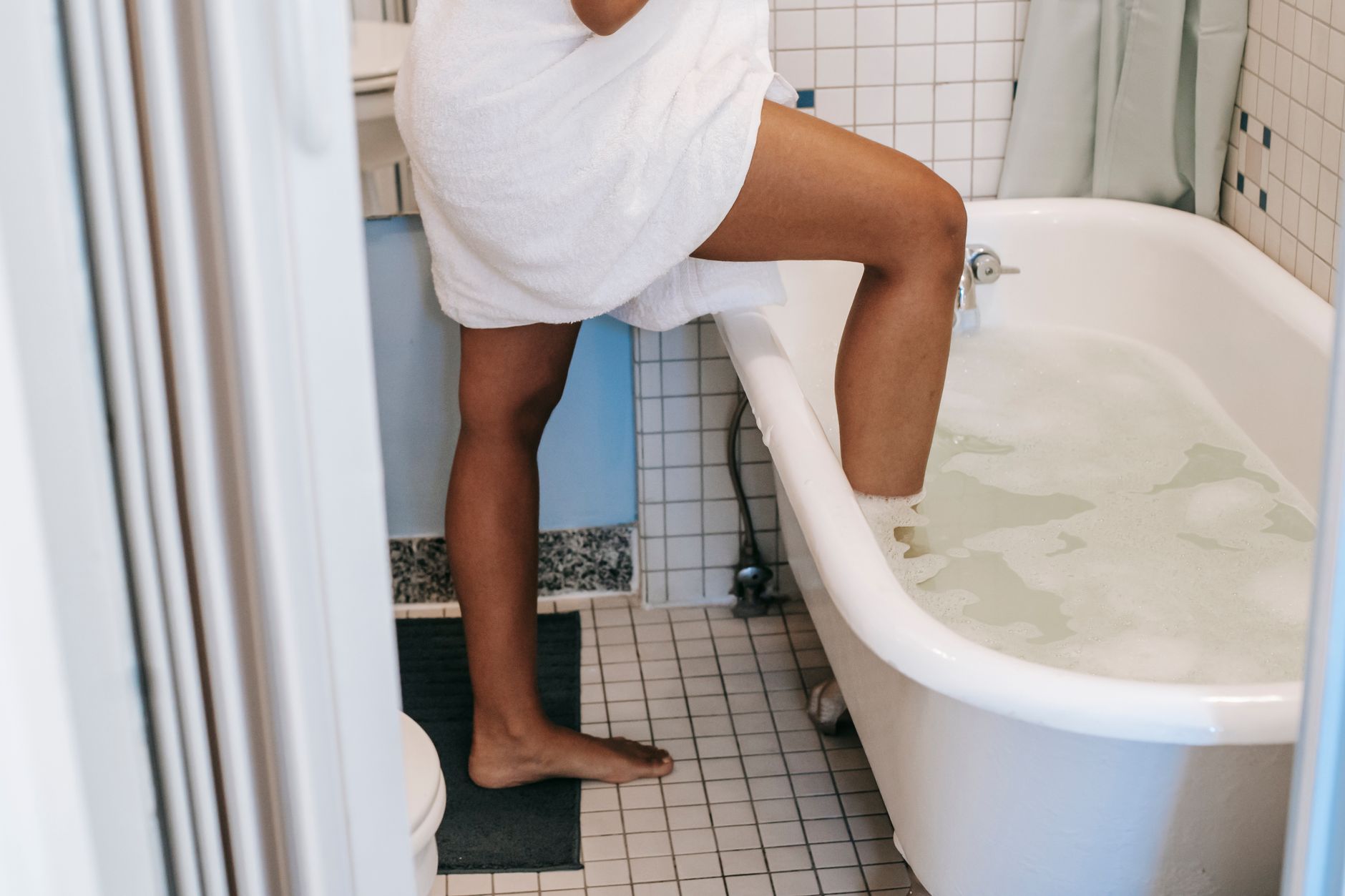 A person stepping into a bathtub