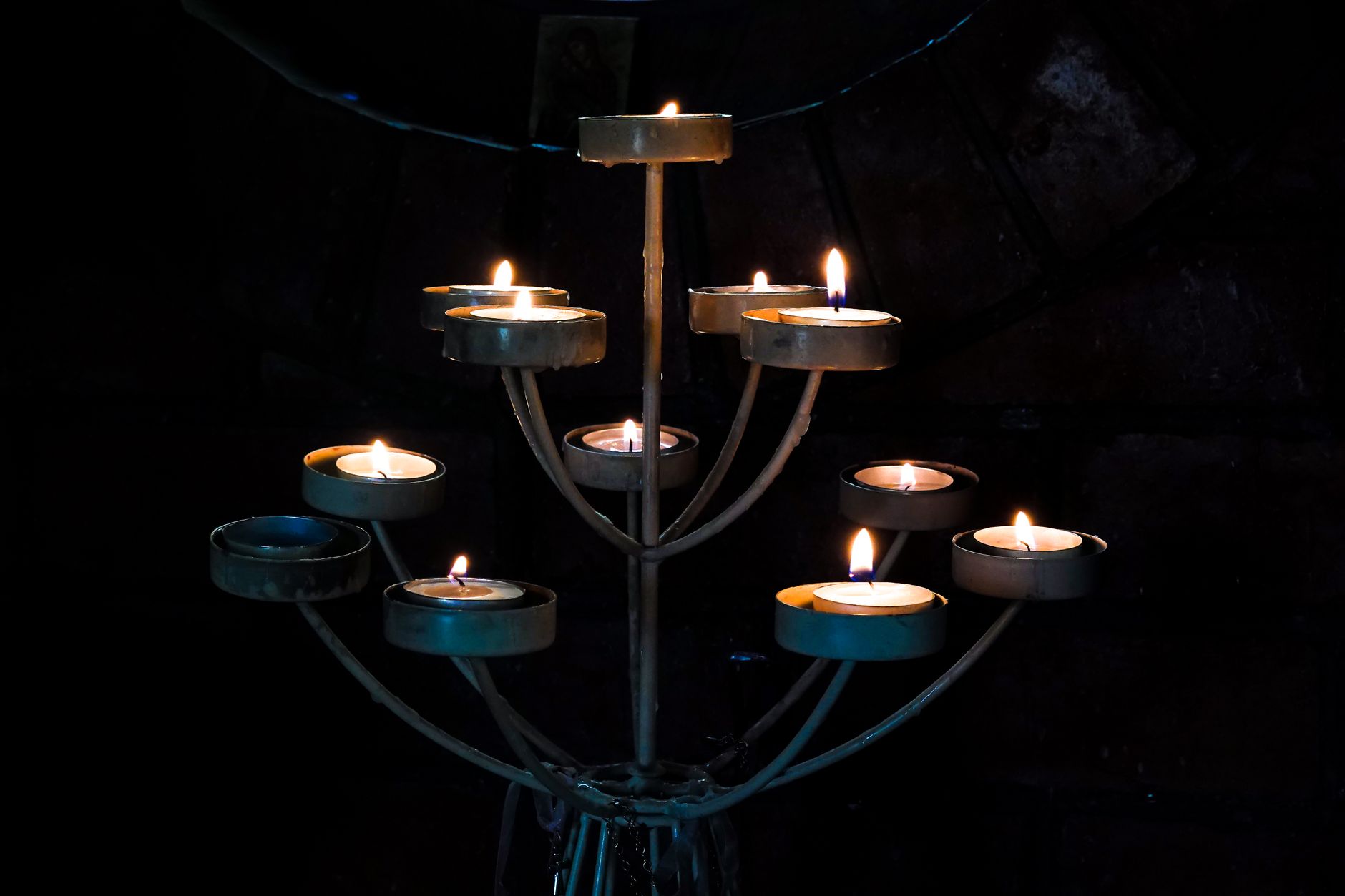 Tea light candles burning on a metal stand in the dark