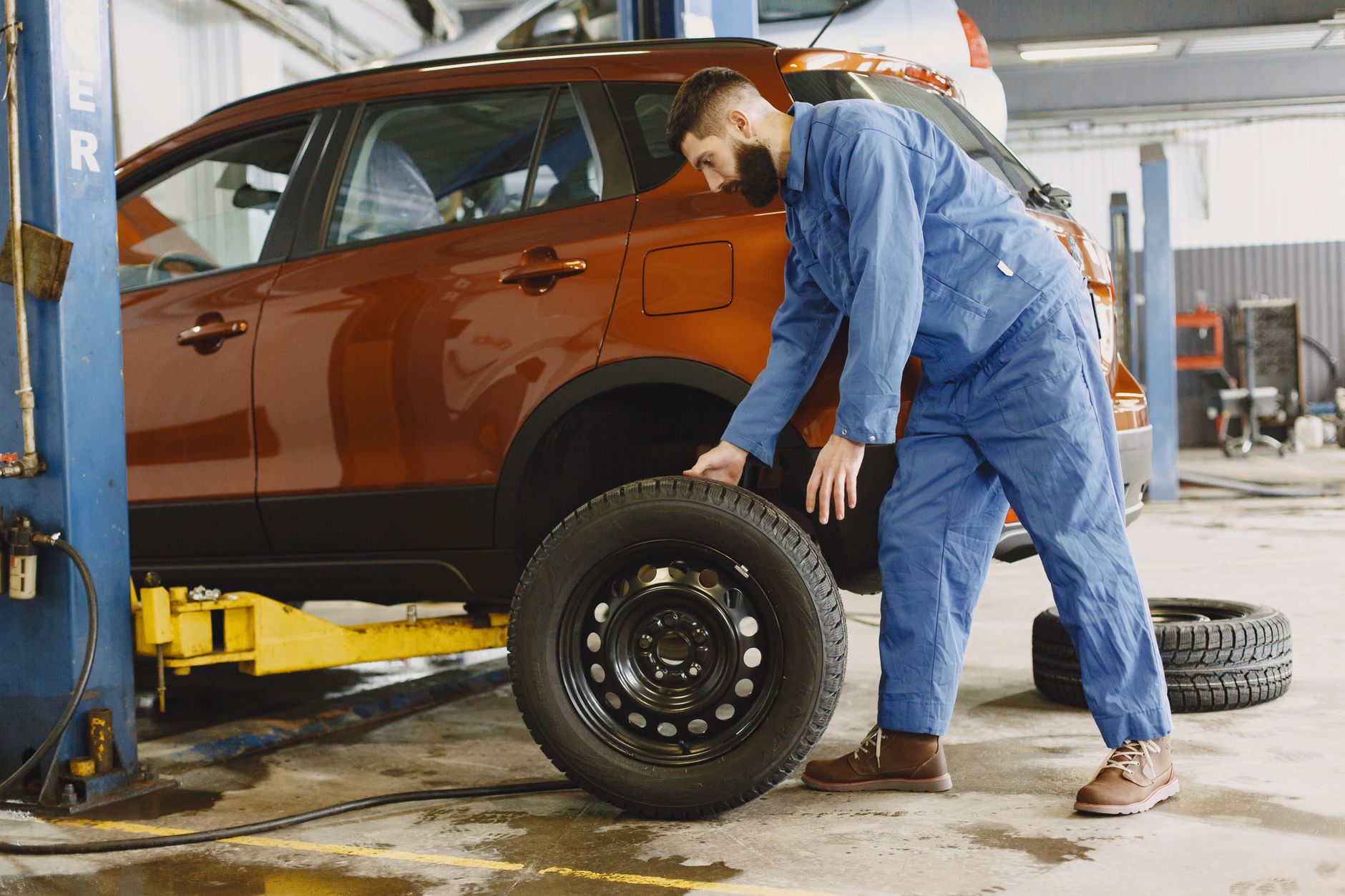 A mechanic fitting a wheel on a lifted car